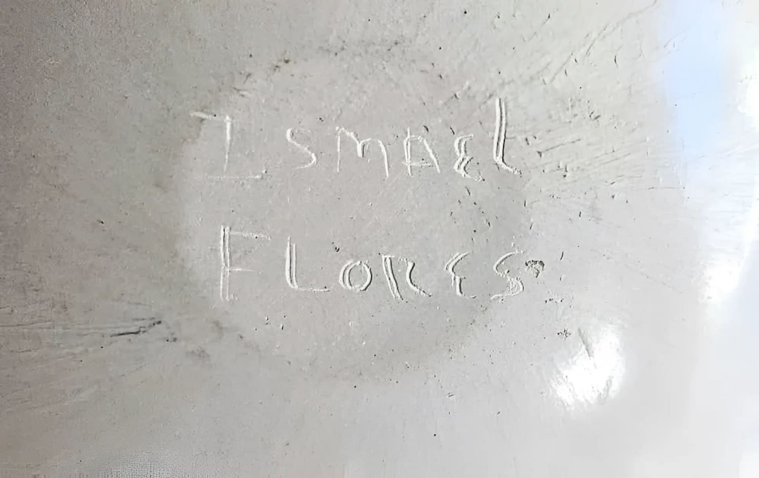 White, textured surface with faint, carved writing.