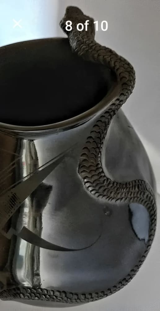 A silver-toned metal pitcher or vase with an intricately detailed snake sculpture wrapped around its body and rim.