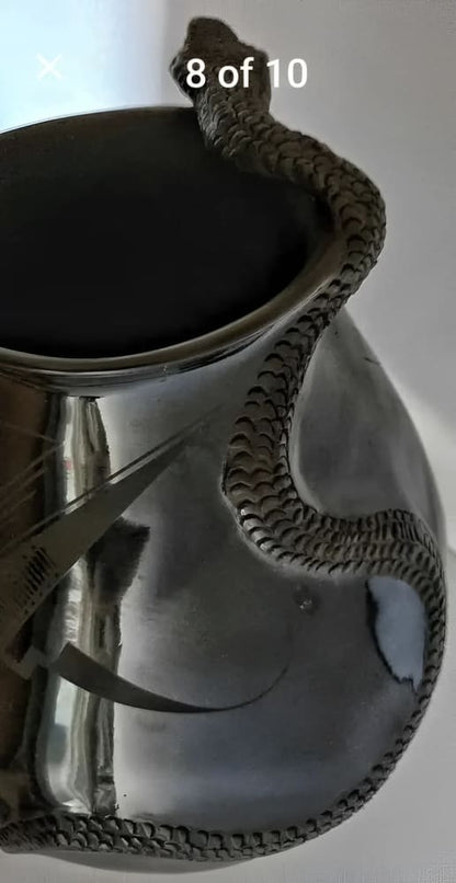 A silver-toned metal pitcher or vase with an intricately detailed snake sculpture wrapped around its body and rim.