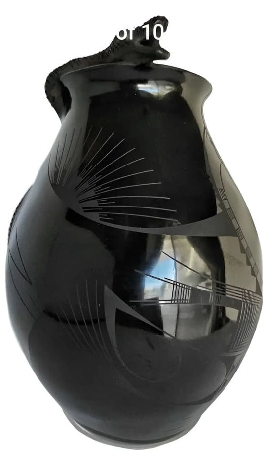 Polished black pottery vase with etched geometric designs and a snake handle.