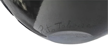 A black glazed pottery vessel with an etched signature.