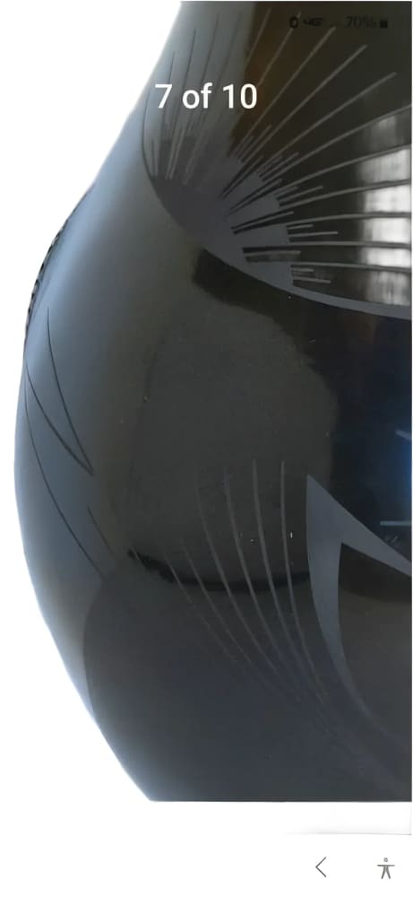 A black, glossy, etched ceramic vase with a radiating pattern.